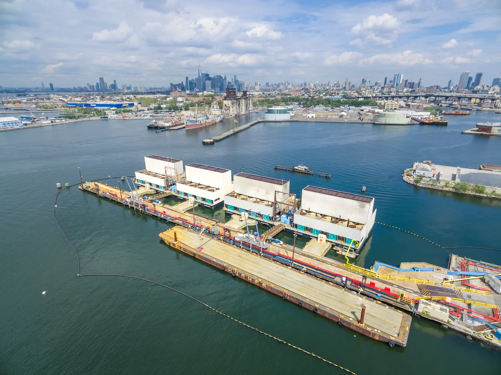 Aerial of floating power barges in the harbor with the city skyline behind — agency campaign work
