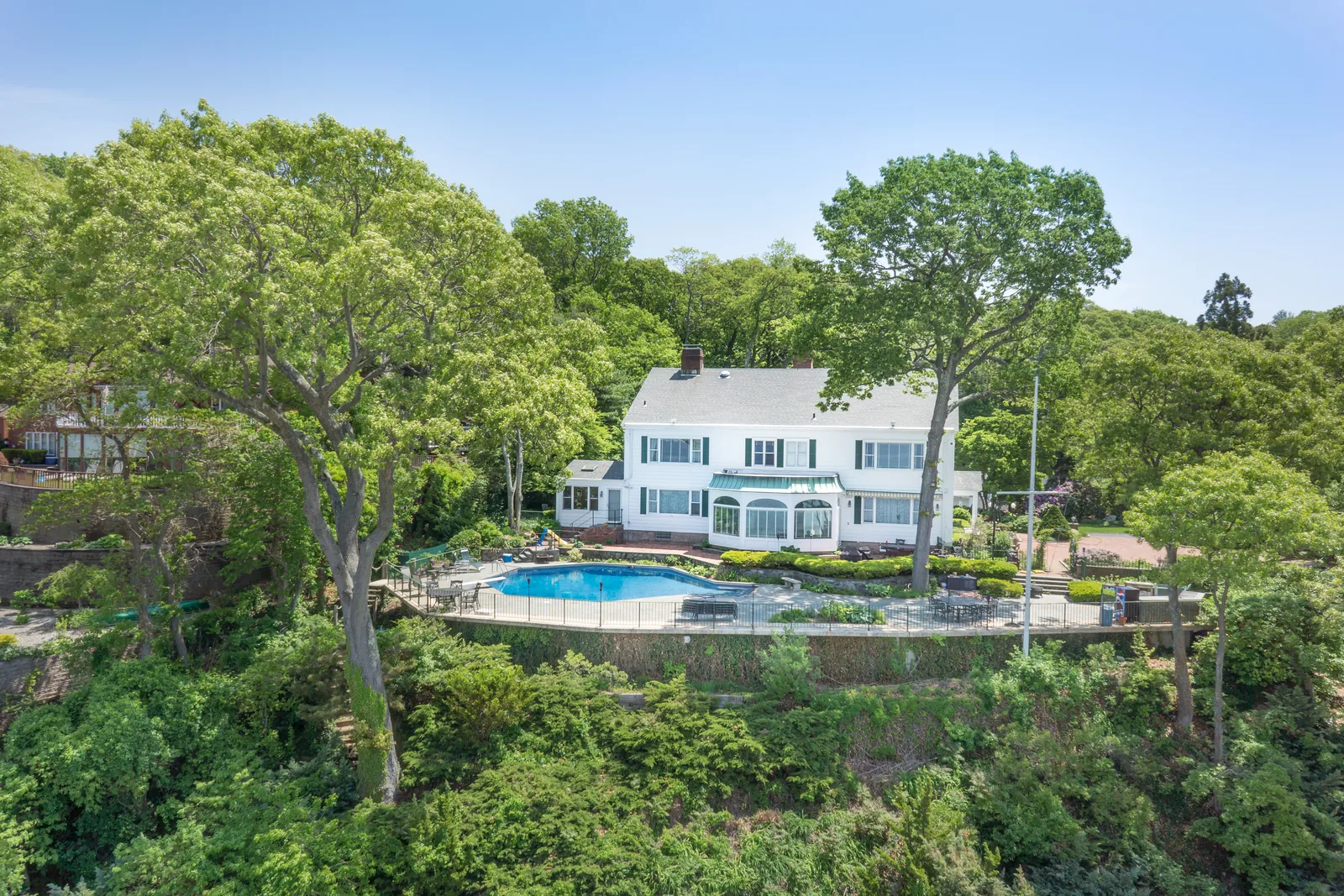 Hillside home and pool from the air, terraced into mature trees