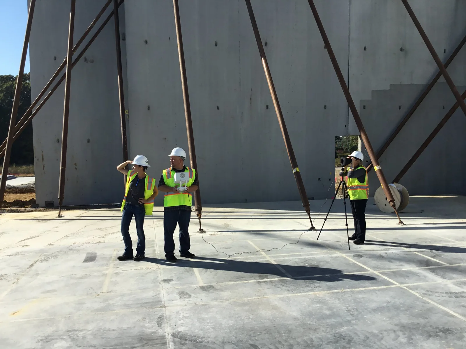 Pilot and visual observer in hard hats and safety vests flying a mission inside a tilt-up construction site