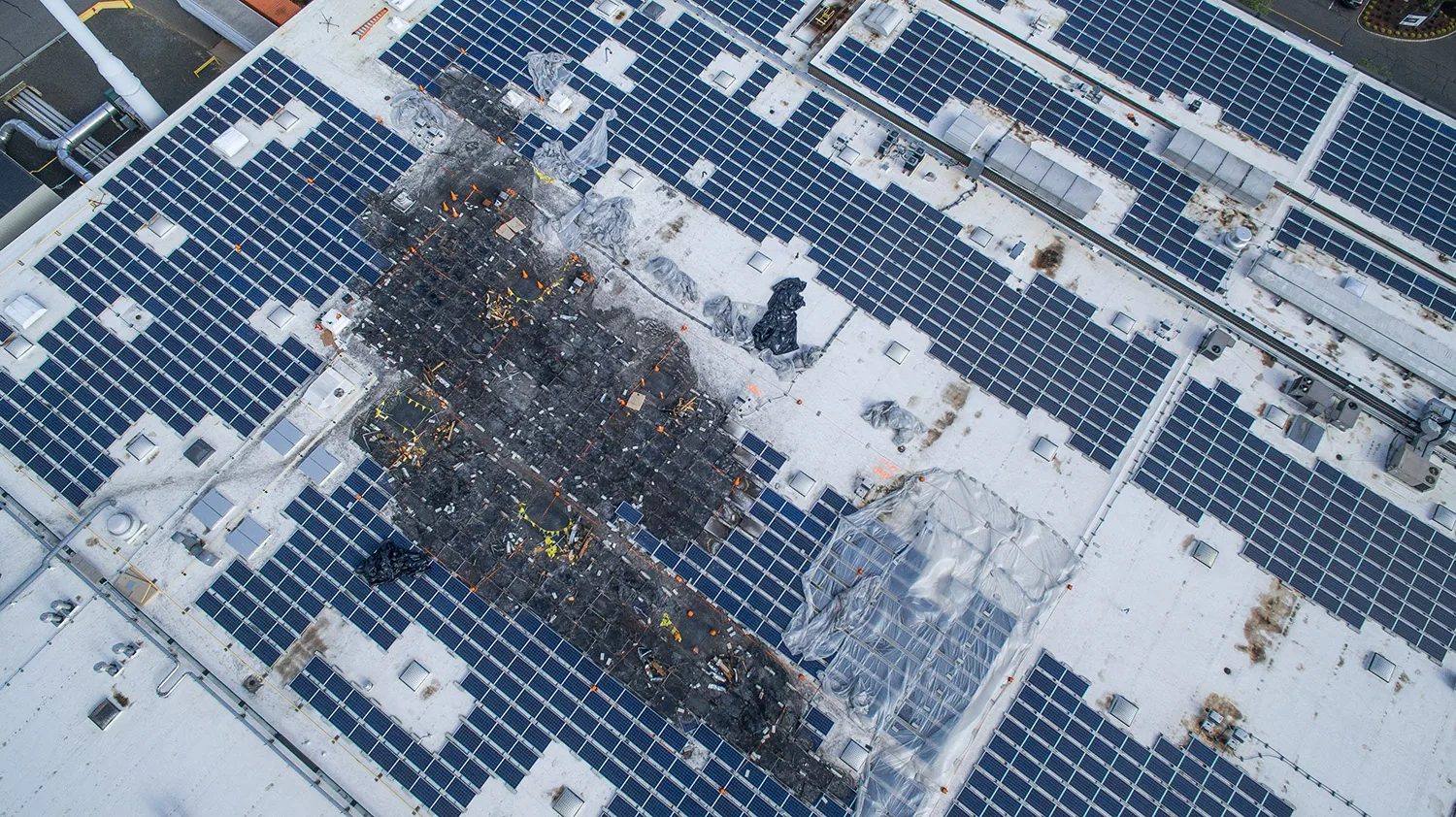 Drone inspection image of a rooftop solar array, documenting the fire-damaged section from above
