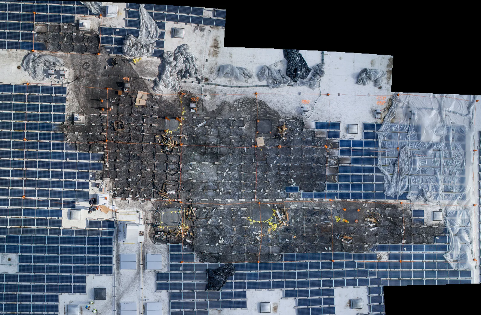 Stitched overhead of a fire-damaged rooftop solar array, showing the full extent of the damage