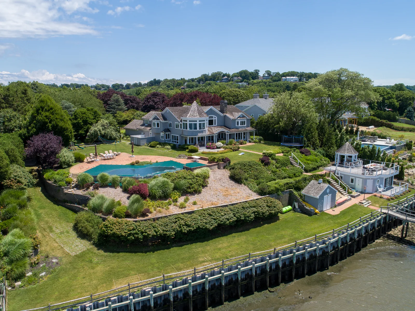Listing aerial of a waterfront estate with pool, bulkhead, and dock