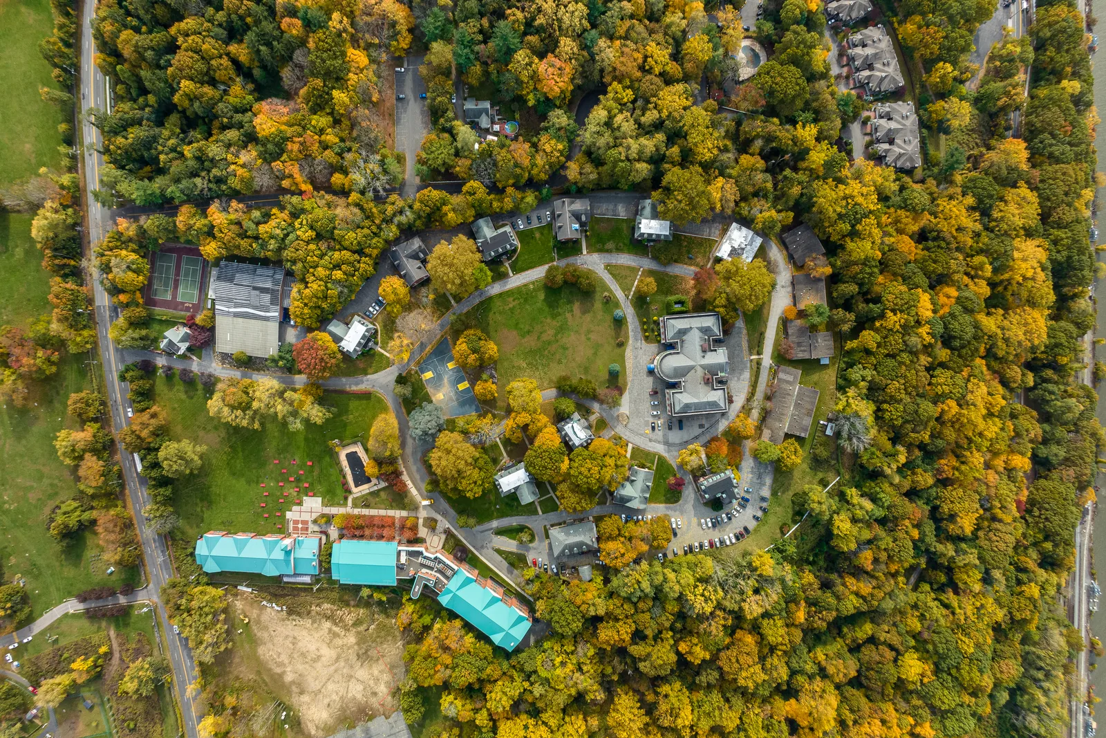 Wooded development site from the air, existing structures and clearings legible through the canopy