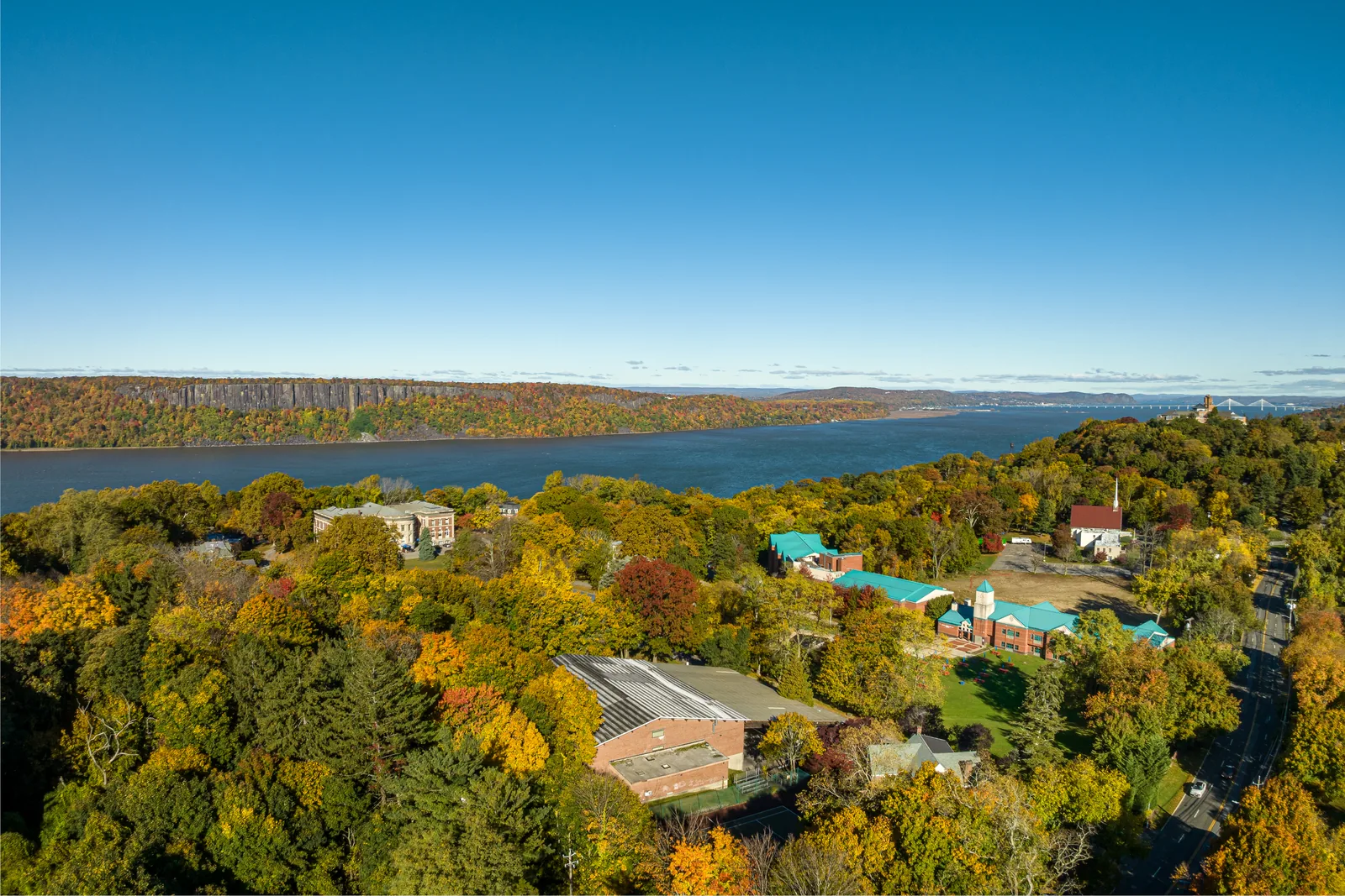 Wooded development site with existing buildings and a river view, photographed in fall